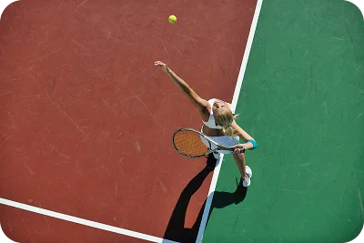 top view of female tennis player serving the ball on a green court, capturing precision, technique, and professional tennis training moment