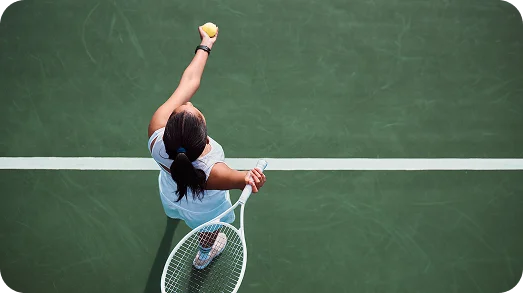 female tennis player performing a powerful serve on a red and green court, showing dynamic movement, athletic performance, and competitive tennis action