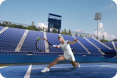 male tennis player hitting a powerful shot on a blue stadium court with empty stands, capturing professional match action, speed, and performance intensity