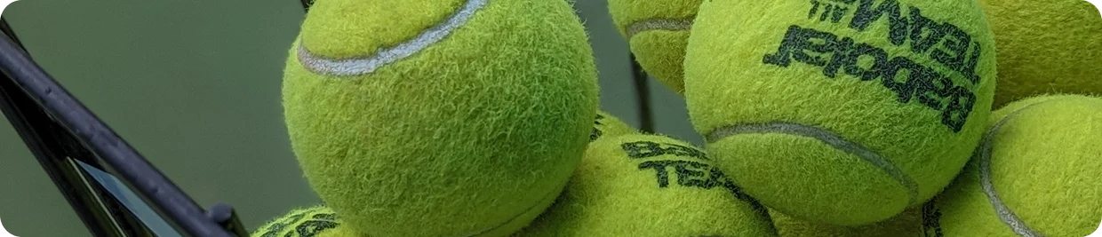 close-up of bright green tennis balls stacked together in a basket showing detailed texture and professional sports equipment used in tennis training and matches